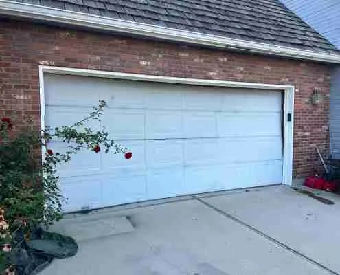 Old worn white garage door before replacement